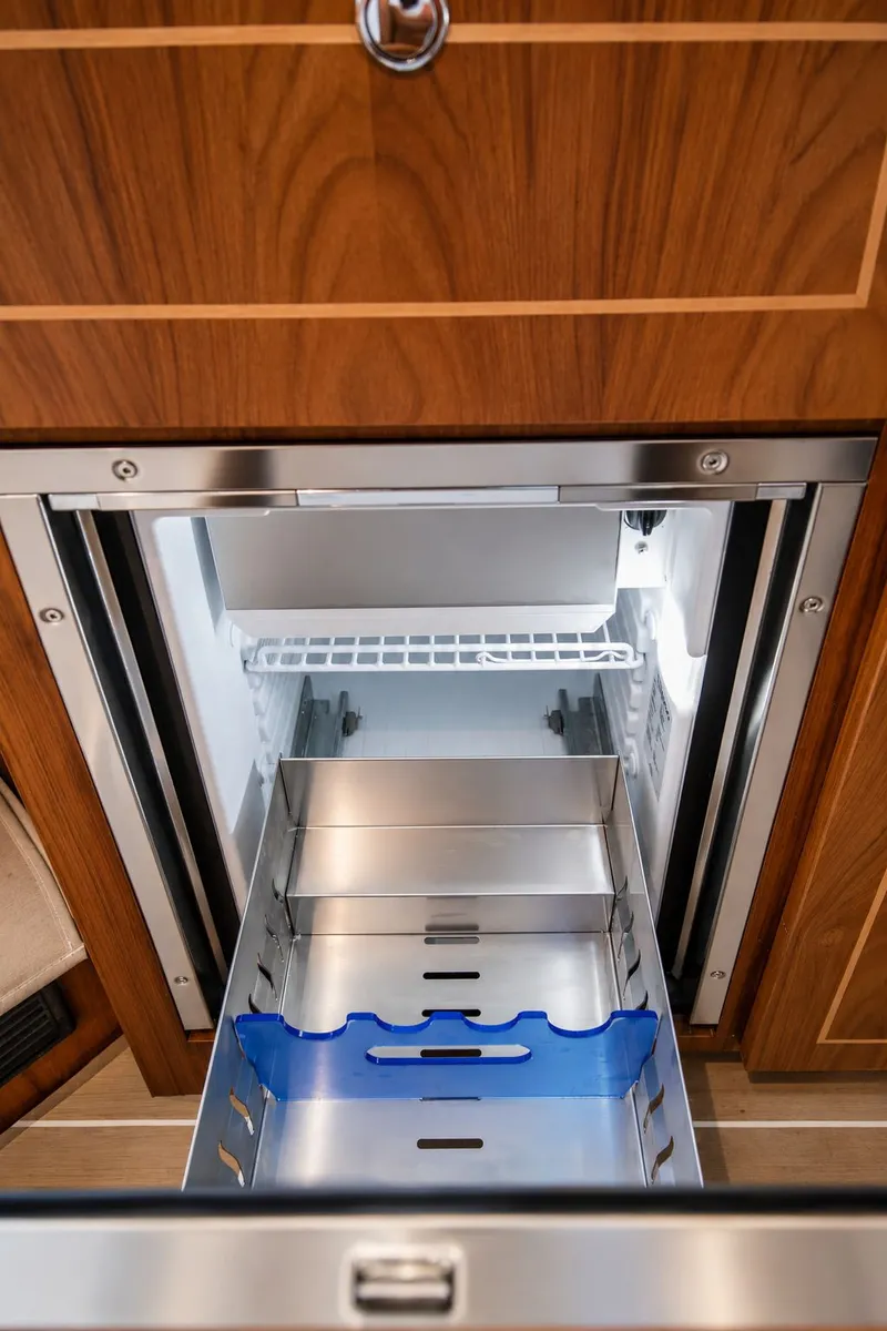 Slide: The Image of An open refrigerator with a blue bottle holder in a wooden cabinet. - 29