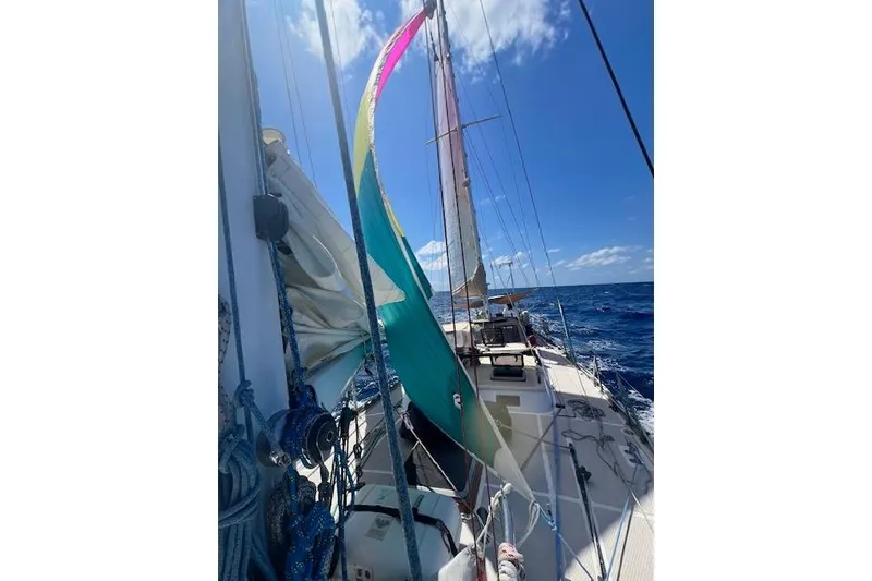 Slide: The Image of Sailing on a 1985 Robert Clark Ketch with colorful sails against a clear blue sky. - 11