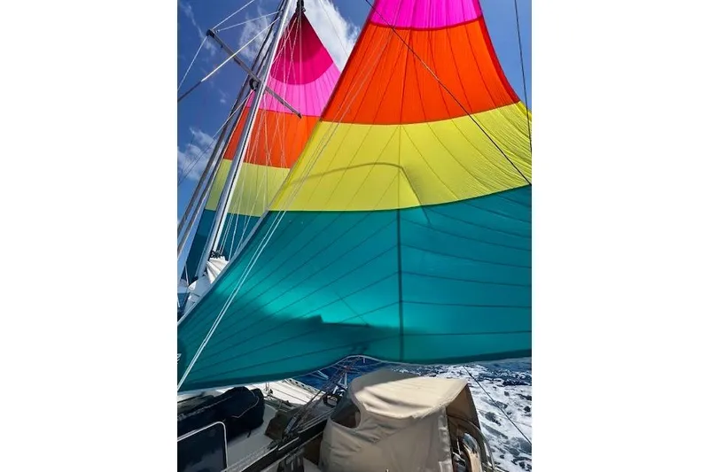 Slide: The Image of Colorful sails on a 1985 Robert Clark Ketch against a clear blue sky. - 13