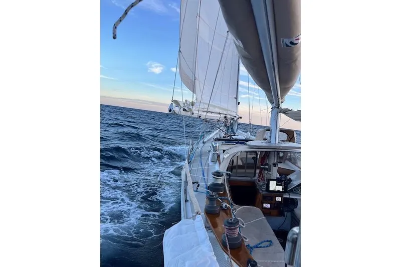 Slide: The Image of Sailing on a 1985 Robert Clark Ketch, ocean view, clear sky, and white sails. - 16