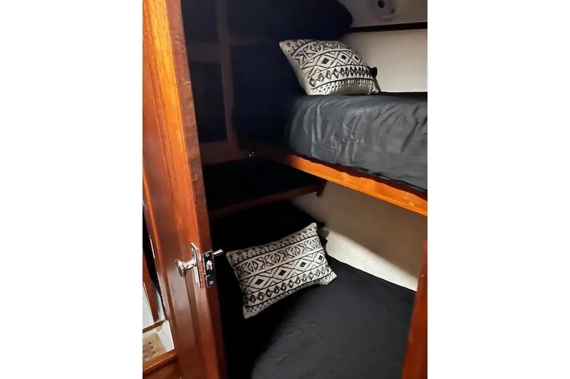 Slide: The Image of Cozy cabin bunks in 1985 Robert Clark Ketch sailboat, featuring patterned pillows and wooden accents. - 51