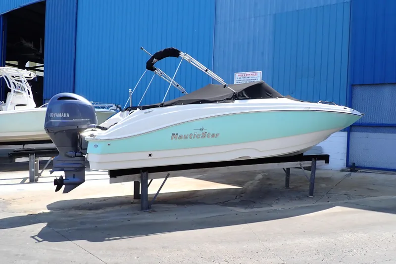 Slide: The Image of 2021 NauticStar 223 DC boat with Yamaha engine, docked near blue building. - 1