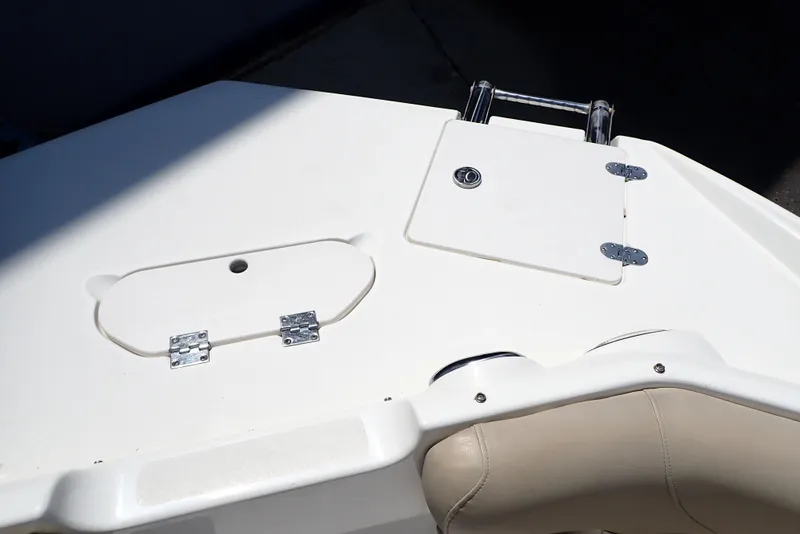 Slide: The Image of 2021 NauticStar 223 DC boat deck with storage compartments and beige seating. - 12