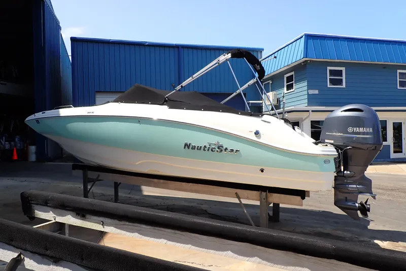 Slide: The Image of 2021 NauticStar 223 DC boat with Yamaha engine, docked near blue buildings. - 2