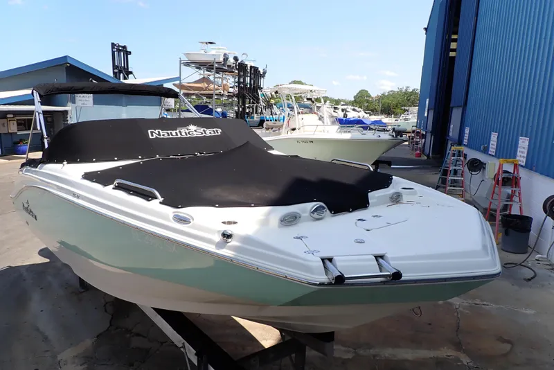 Slide: The Image of 2021 NauticStar 223 DC boat with cover, docked at a marina. - 3