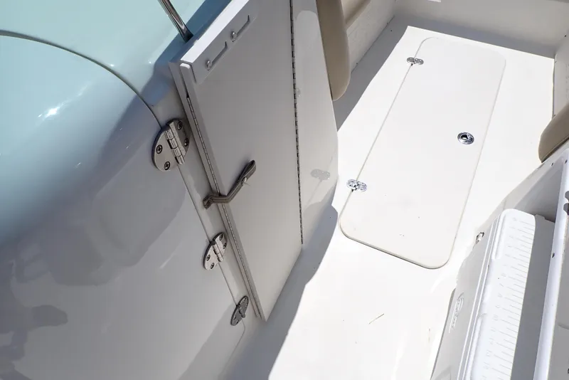Slide: The Image of 2021 NauticStar 223 DC boat interior, featuring a sleek white deck and storage compartment. - 34