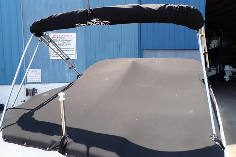 Slide: The Image of 2021 NauticStar 223 DC boat with black cover and bimini top. - 4