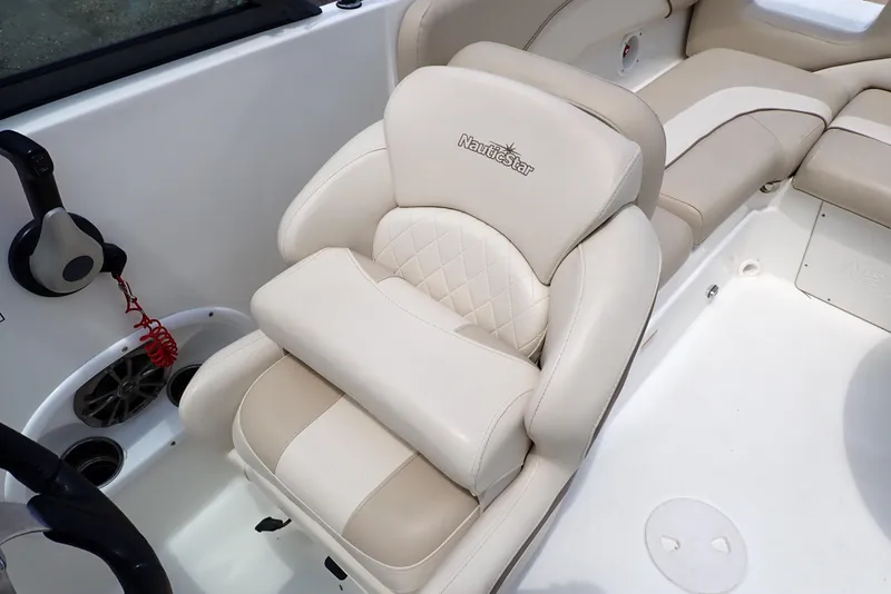 Slide: The Image of 2021 NauticStar 223 DC boat interior with beige cushioned seating and steering area. - 42