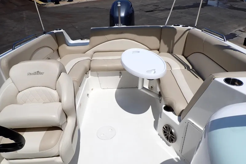 Slide: The Image of 2021 NauticStar 223 DC boat interior with beige seating and round table. - 8