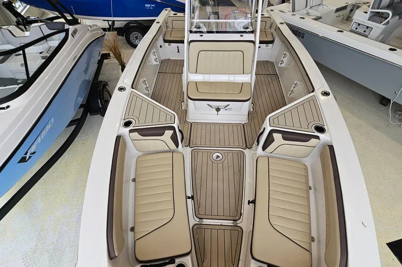 Slide: The Image of 2021 Yamaha Boats 210 FSH Sport interior with tan seating and wood-style flooring. - 12