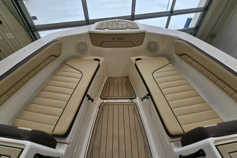 Slide: The Image of 2021 Yamaha Boats 210 FSH Sport interior with beige seating and wood accents. - 16