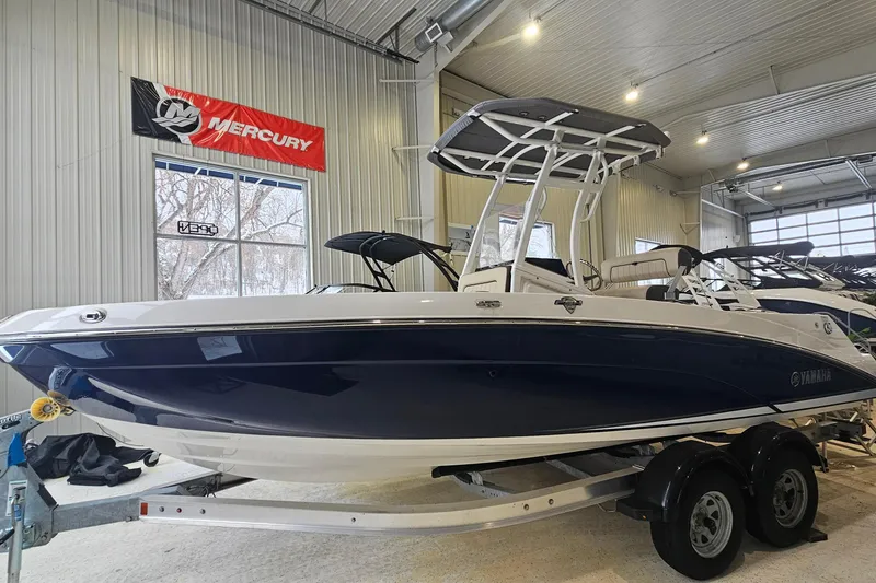 Slide: The Image of 2021 Yamaha Boats 210 FSH Sport in showroom, blue and white design, on trailer. - 2