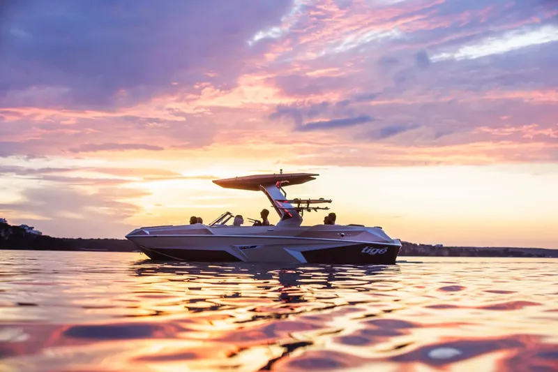Slide: The Image of Manufacturer Provided Image: 2026 Tigé 22RZX boat cruising at sunset on calm water. - 2