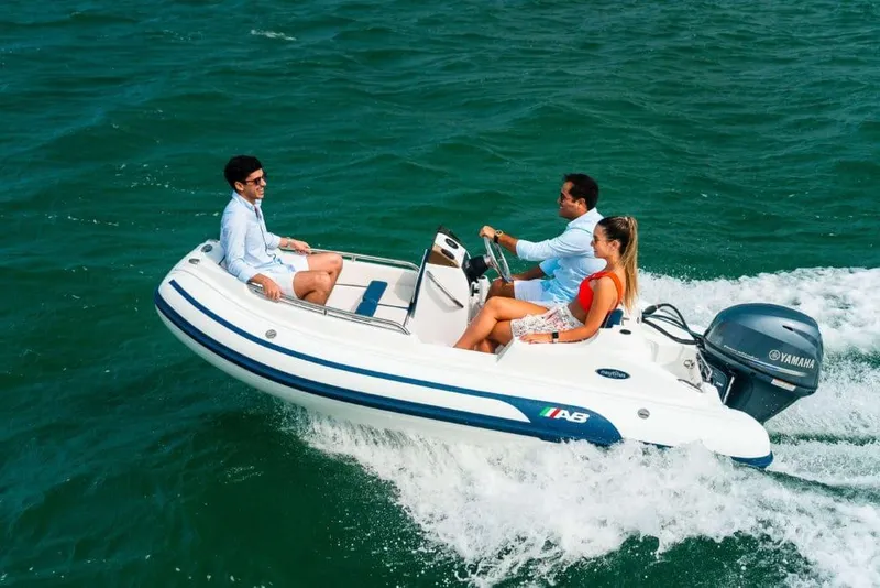 Slide: The Image of 2024 AB Inflatables Nautilus 12 DLX cruising with three passengers on open water. - 9