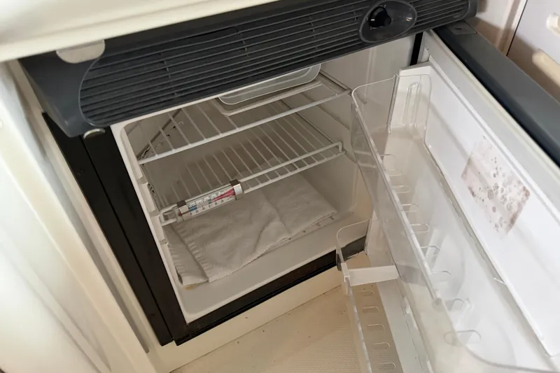 Slide: The Image of Open refrigerator inside a 2006 Sea Ray 40 Sundancer boat, showing empty shelves and door storage. - 32