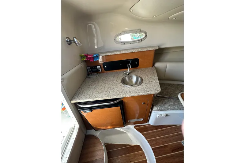 Slide: The Image of 2011 Robalo R245 Walkaround cabin interior with kitchenette, sink, and wooden flooring. - 12