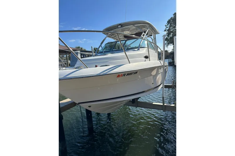 Slide: The Image of 2011 Robalo R245 Walkaround boat on lift, docked by waterfront. - 2