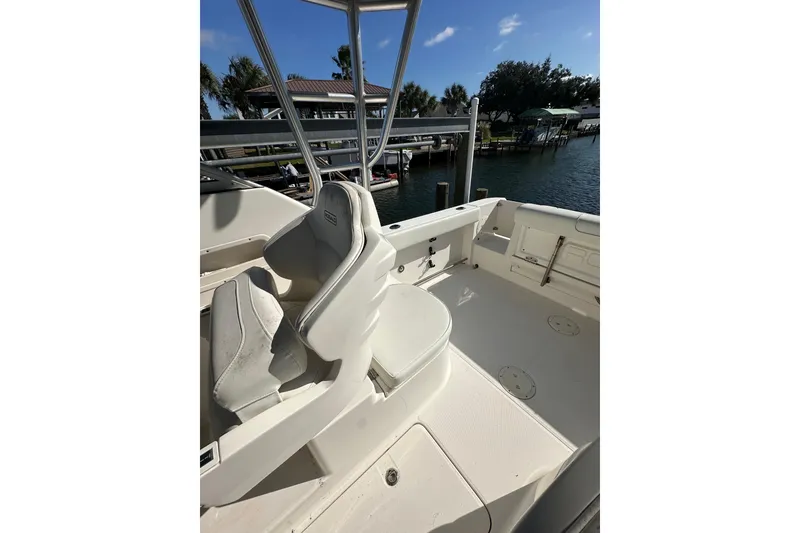 Slide: The Image of 2011 Robalo R245 Walkaround boat interior with seating, docked by the water. - 8