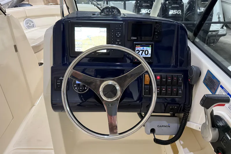 Slide: The Image of 2014 Pursuit DC 265 Dual Console boat interior with white seating and "Nautica" pillow. - 15