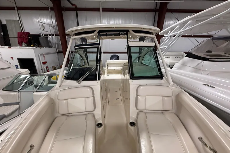 Slide: The Image of 2014 Pursuit DC 265 Dual Console boat interior with seating and windshield in a showroom. - 59