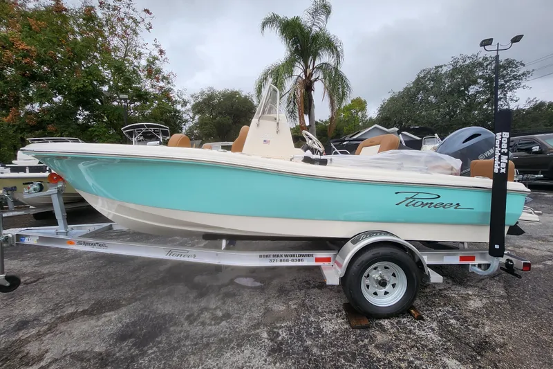 Slide: The Image of 2026 Pioneer 180 Islander boat on trailer, turquoise and white design, parked outdoors. - 11