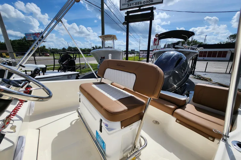 Slide: The Image of 2026 Pioneer 180 Islander boat interior with seating and steering wheel under a sunny sky. - 4