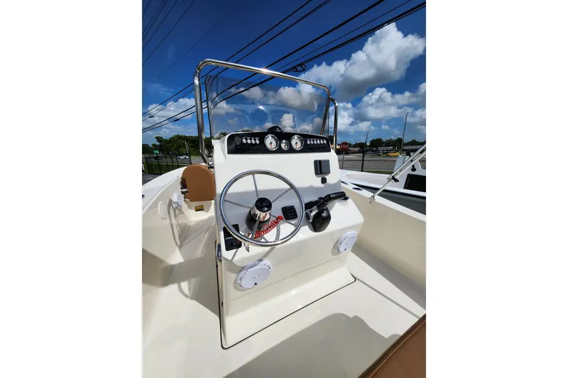 Slide: The Image of 2026 Pioneer 180 Islander boat dashboard with steering wheel and controls under a clear blue sky. - 5
