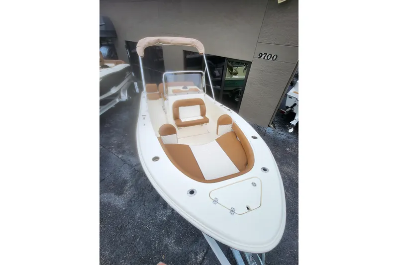 Slide: The Image of 2026 Pioneer 180 Islander boat with tan seating and canopy, docked outdoors. - 7