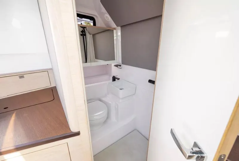 Slide: The Image of 2025 Axopar 45 Cross Top boat interior bathroom with modern fixtures and wooden cabinetry. - 12