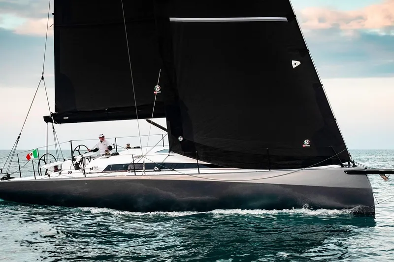 Slide: The Image of 2024 Neo 43 Romo sailboat with black sails on open water. - 2