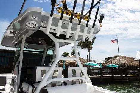 Slide: The Image of Manufacturer Provided Image: 2026 Blackfin 302 CC boat with fishing rods, docked near a waterfront restaurant. - 5