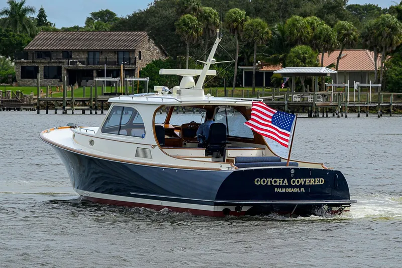 The Image of 2006 Hinckley Talaria 40 yacht with American flag, cruising near waterfront homes. - 0