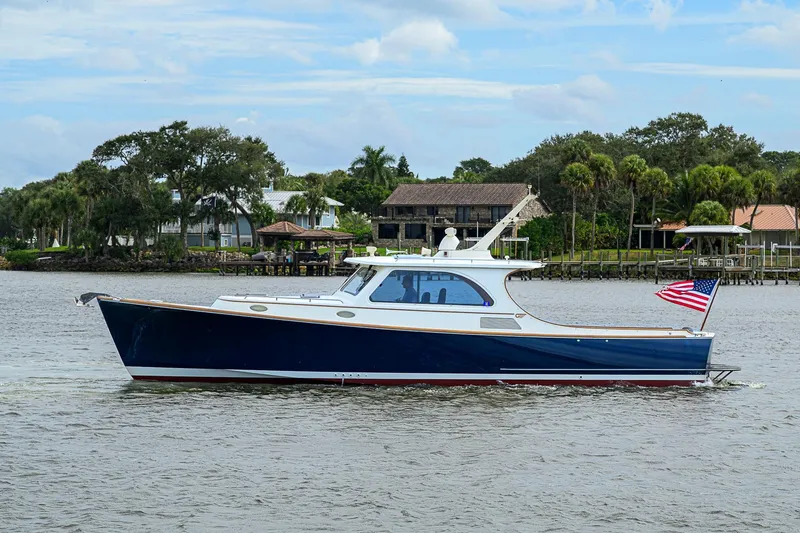 Slide: The Image of 2006 Hinckley Talaria 40 yacht cruising on a scenic waterway with American flag. - 1