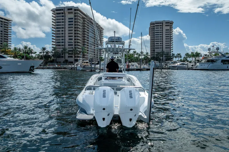 Slide: The Image of 2021 Yellowfin 26 Hybrid boat in marina, surrounded by tall buildings and yachts. - 10