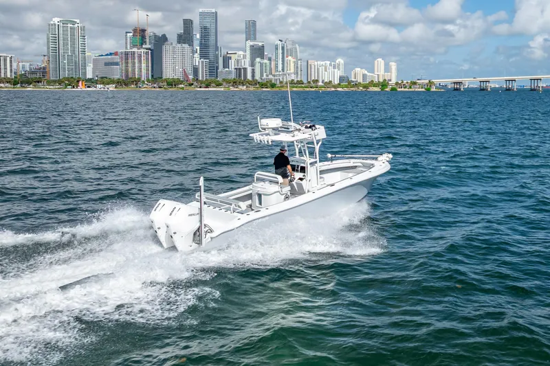 Slide: The Image of 2021 Yellowfin 26 Hybrid boat cruising near city skyline on a sunny day. - 11