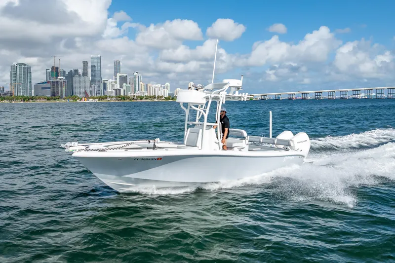 Slide: The Image of 2021 Yellowfin 26 Hybrid boat cruising near city skyline on a sunny day. - 13