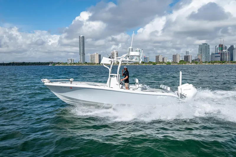 Slide: The Image of 2021 Yellowfin 26 Hybrid boat cruising near city skyline on a sunny day. - 14