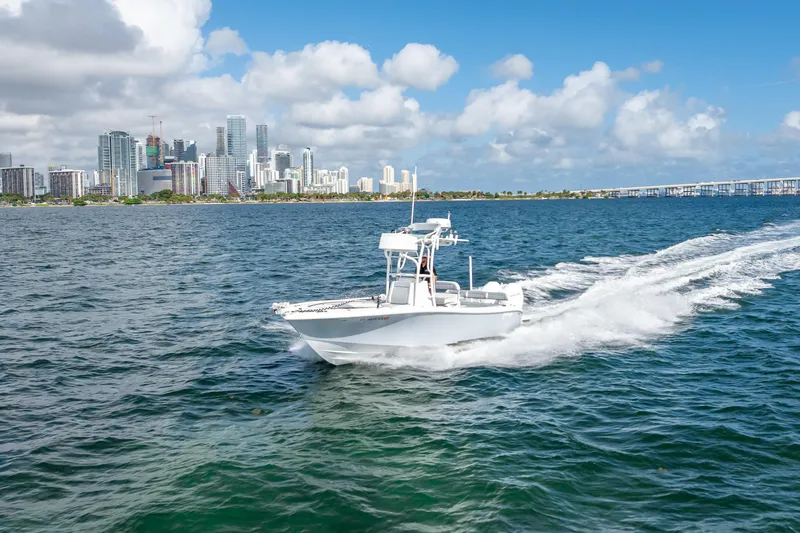Slide: The Image of 2021 Yellowfin 26 Hybrid boat cruising near city skyline on a sunny day. - 15