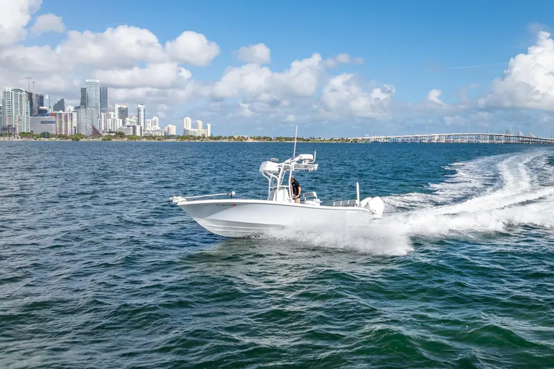 Slide: The Image of 2021 Yellowfin 26 Hybrid boat cruising near city skyline on a sunny day. - 16