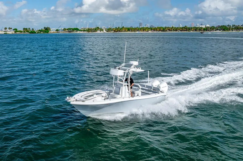 Slide: The Image of 2021 Yellowfin 26 Hybrid boat cruising on blue ocean near lush coastline. - 19