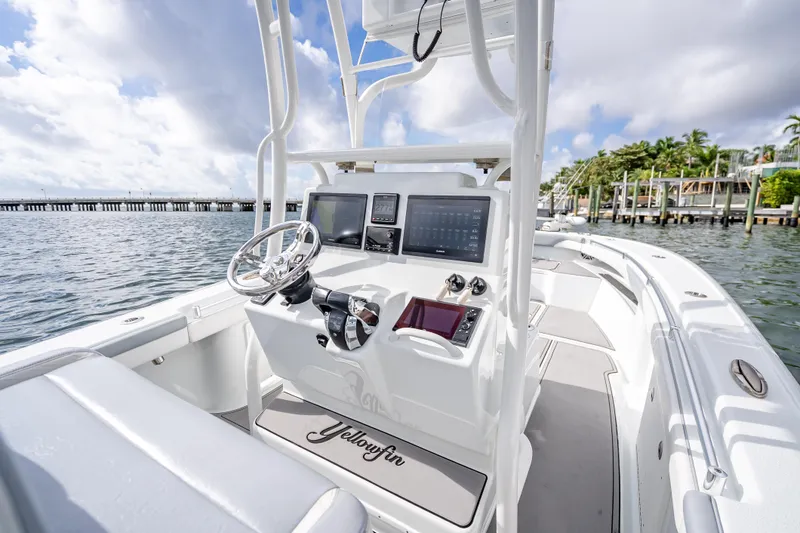 Slide: The Image of 2021 Yellowfin 26 Hybrid boat interior with modern dashboard and steering, docked by the water. - 27