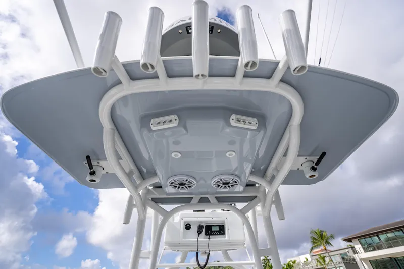 Slide: The Image of 2021 Yellowfin 26 Hybrid boat's T-top with rod holders and speakers against cloudy sky. - 29