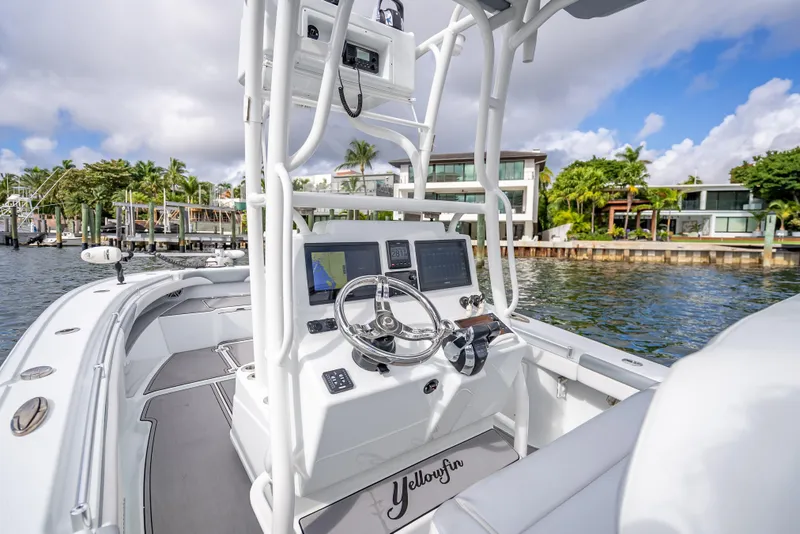 Slide: The Image of 2021 Yellowfin 26 Hybrid boat with modern dashboard, docked near waterfront homes. - 30