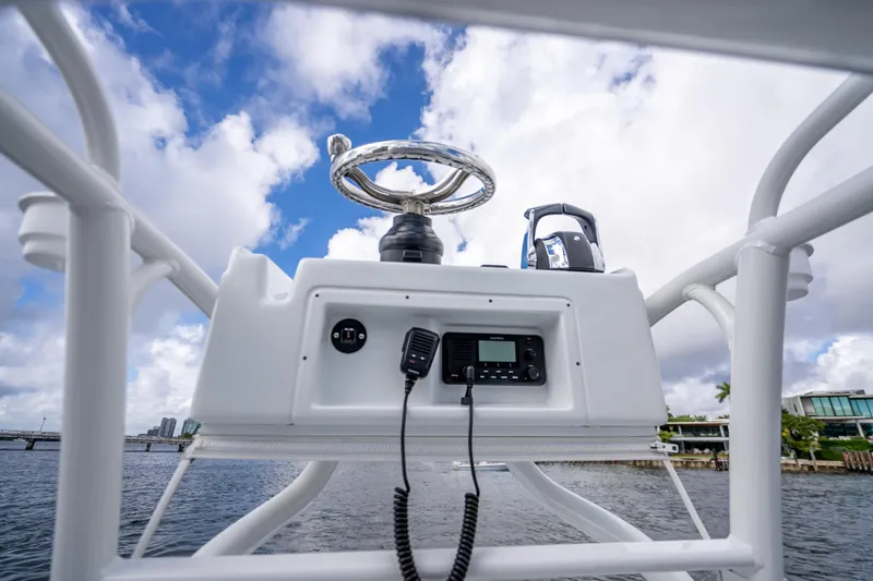 Slide: The Image of 2021 Yellowfin 26 Hybrid boat console with steering wheel and radio, under a cloudy sky. - 33