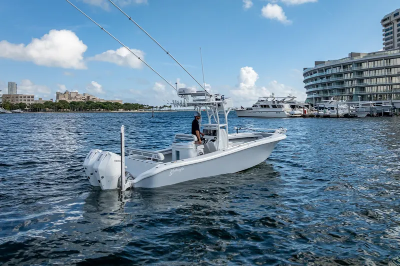 Slide: The Image of 2021 Yellowfin 26 Hybrid boat cruising near marina with modern buildings in background. - 8