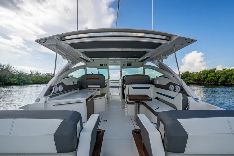 Slide: The Image of 2021 Tiara Yachts 38 LX interior with seating, table, and canopy on a calm waterway. - 13