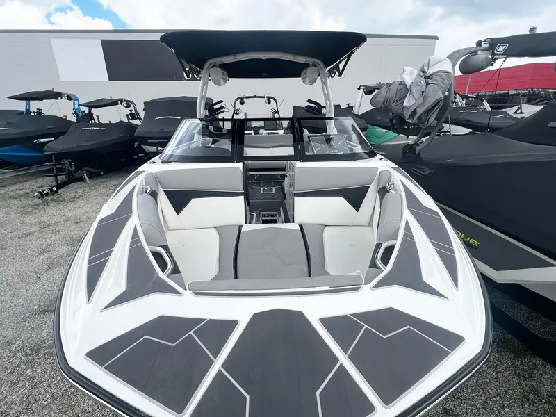 Slide: The Image of 2023 Supreme S220 boat with sleek design and spacious seating, docked outdoors. - 2
