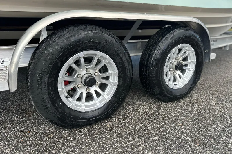 Slide: The Image of Trailer wheels of 2023 Cobia 240 Center Console on wet pavement. - 10