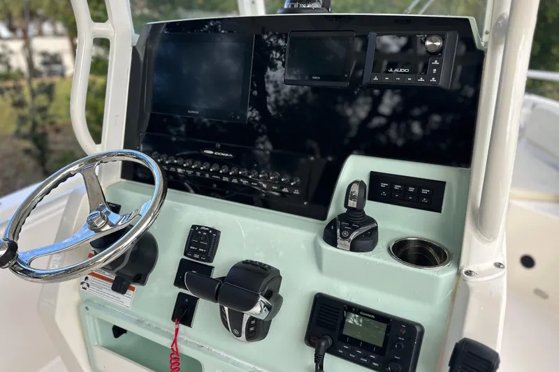 Slide: The Image of 2023 Cobia 240 Center Console boat dashboard with steering wheel and electronic controls. - 13