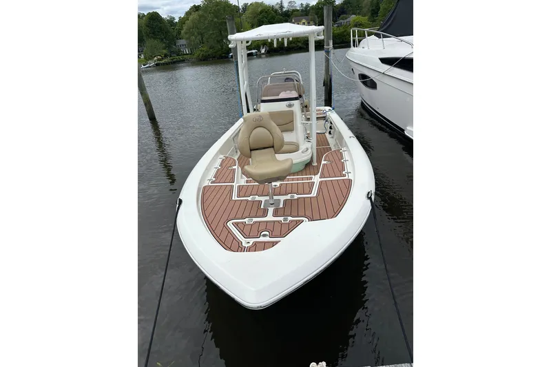 Slide: The Image of 2022 NauticStar 227 XTS boat docked, featuring sleek design and wood-patterned deck. - 4